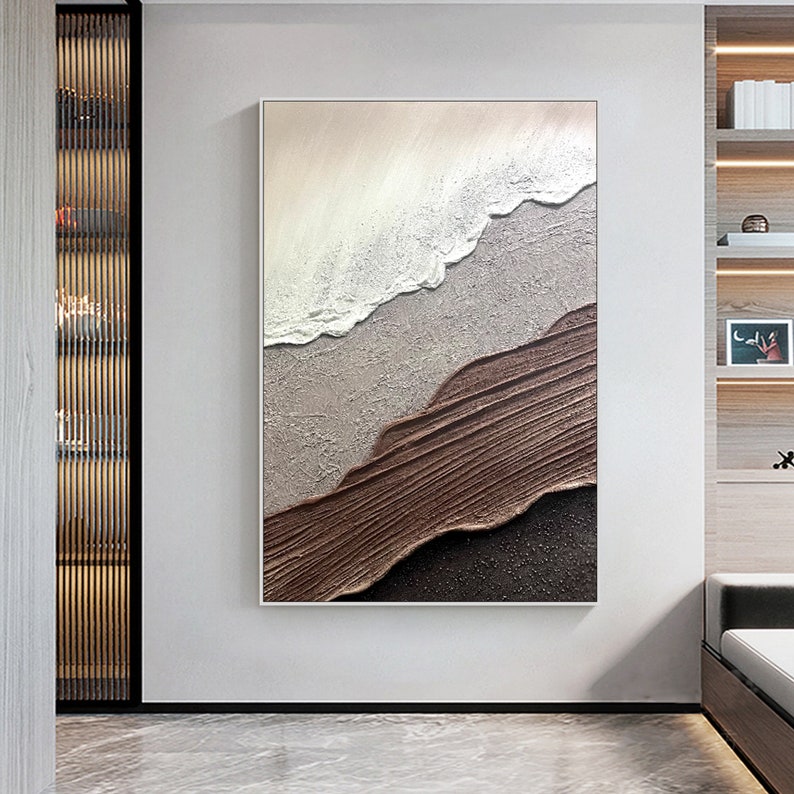 May include: Abstract painting with brown, white, and gray textured brushstrokes. The painting depicts a wave crashing on a sandy beach.