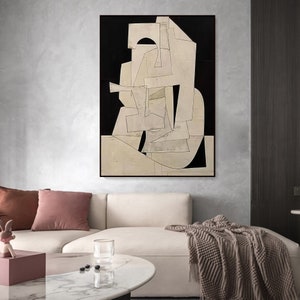 May include: Abstract art print with geometric shapes in white and black on a cream background. The print is framed and hanging on a wall.