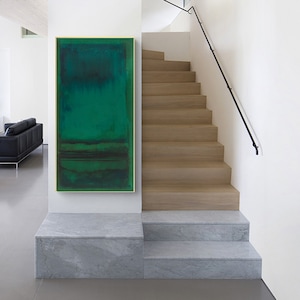 Puede incluir: Pintura abstracta en tonos verdes, enmarcada en oro, colgada en una pared blanca sobre un conjunto de escaleras de m&aacute;rmol.