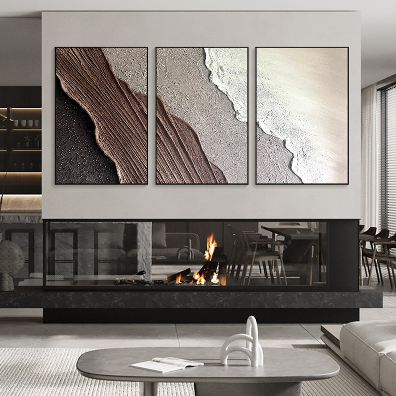 May include: Three abstract paintings in black frames, each depicting a different section of a beach scene with brown, white, and beige colors.