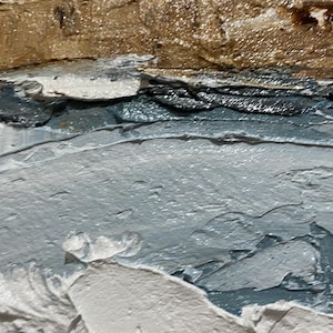 May include: Close-up of an abstract painting with textured brushstrokes. The artwork features layers of color, including shades of gray, blue, and brown, creating a sense of depth and movement. The thick application of paint adds a tactile quality.