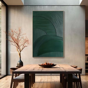 May include: A framed abstract wall art piece with a textured, dark green design. The artwork features curved and linear patterns, creating a layered effect. The piece is displayed in a modern dining room setting.