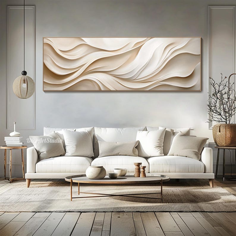 May include: A large abstract painting with flowing white and beige lines, hanging above a white sofa with beige pillows in a living room setting.