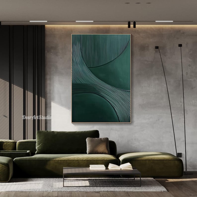 May include: A large, abstract wall art piece with a textured, dark green design. The artwork features curved lines and a gold frame. The piece is displayed above a green sofa in a modern living room setting.