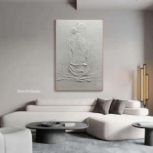 Puede incluir: Pintura abstracta texturizada blanca de una persona sentada de espaldas al espectador. La pintura est&aacute; en una pared blanca en un sal&oacute;n.