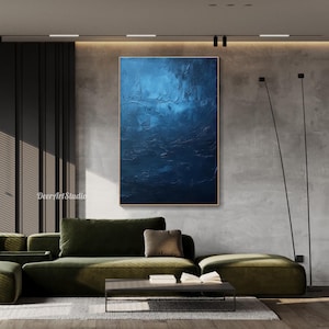 Puede incluir: Pintura abstracta en tonos azules con un efecto texturizado y en capas. La pintura se muestra en una pared en un ambiente de sala de estar moderna.