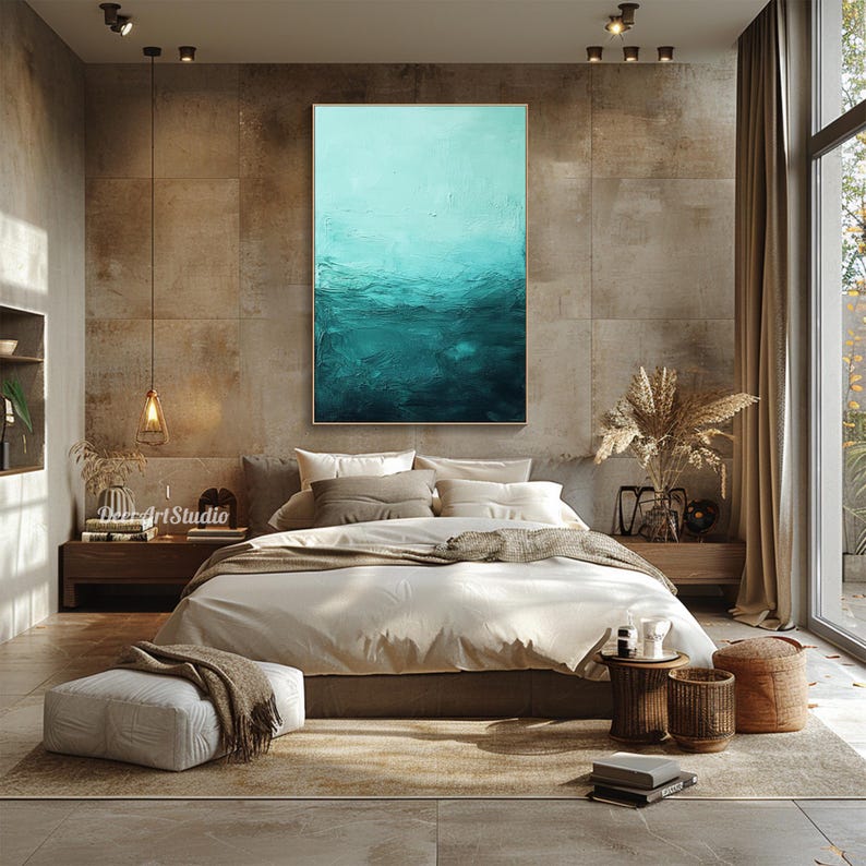 Puede incluir: Una pintura abstracta en azul y verde azulado en un marco dorado cuelga sobre una cama con ropa de cama blanca y almohadas marrones en un dormitorio moderno con una mesita de noche de madera y una ventana grande.
