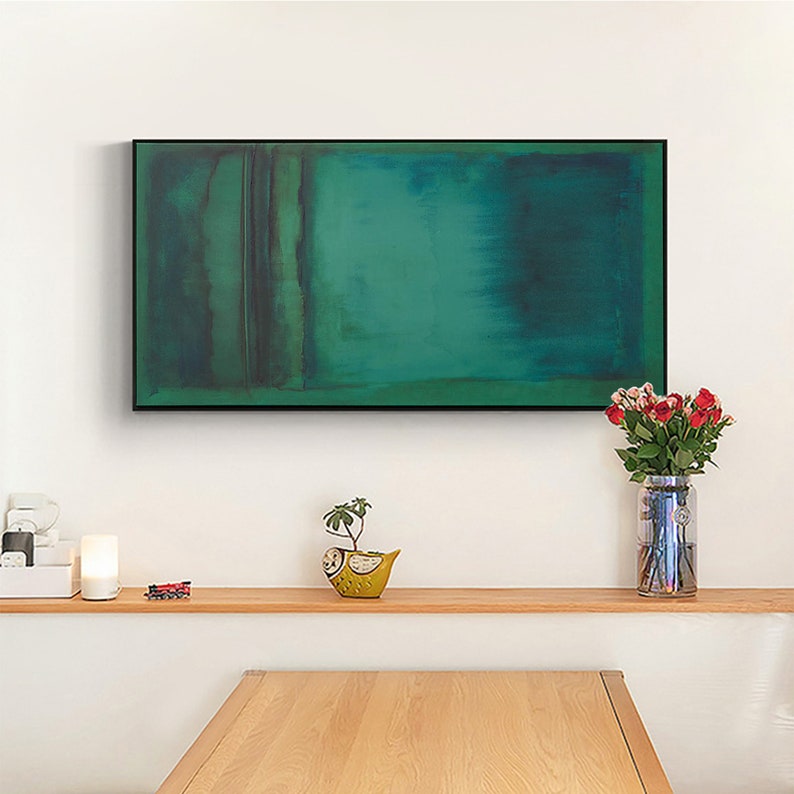 Puede incluir: Una pintura abstracta enmarcada con un esquema de color verde y azul. La pintura est&aacute; colgada en una pared blanca sobre una estanter&iacute;a de madera con una peque&ntilde;a planta en maceta y un jarr&oacute;n de flores rojas.