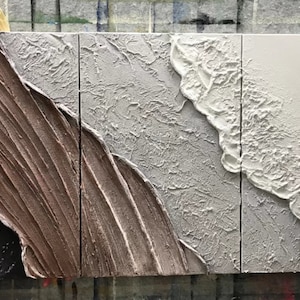 May include: Three-piece abstract wall art set with textured paint in shades of brown, gray, and white. The panels feature a wave-like design with raised edges.