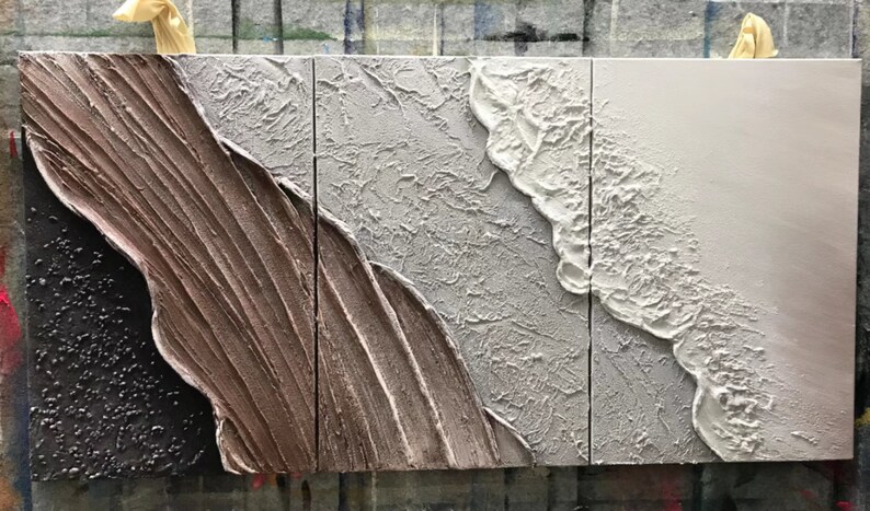May include: Three-piece abstract wall art set with textured paint in shades of brown, gray, and white. The panels feature a wave-like design with raised edges.