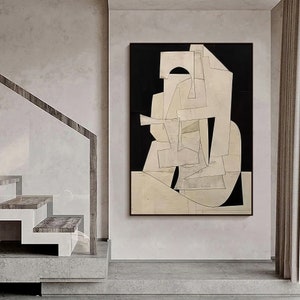May include: Abstract art print with geometric shapes in white and black on a beige background. The print is framed in a black frame.