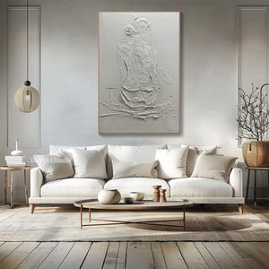 Puede incluir: Pintura blanca texturizada de una persona sentada de espaldas al espectador. La pintura est&aacute; sobre un lienzo blanco y tiene un efecto en relieve tridimensional.
