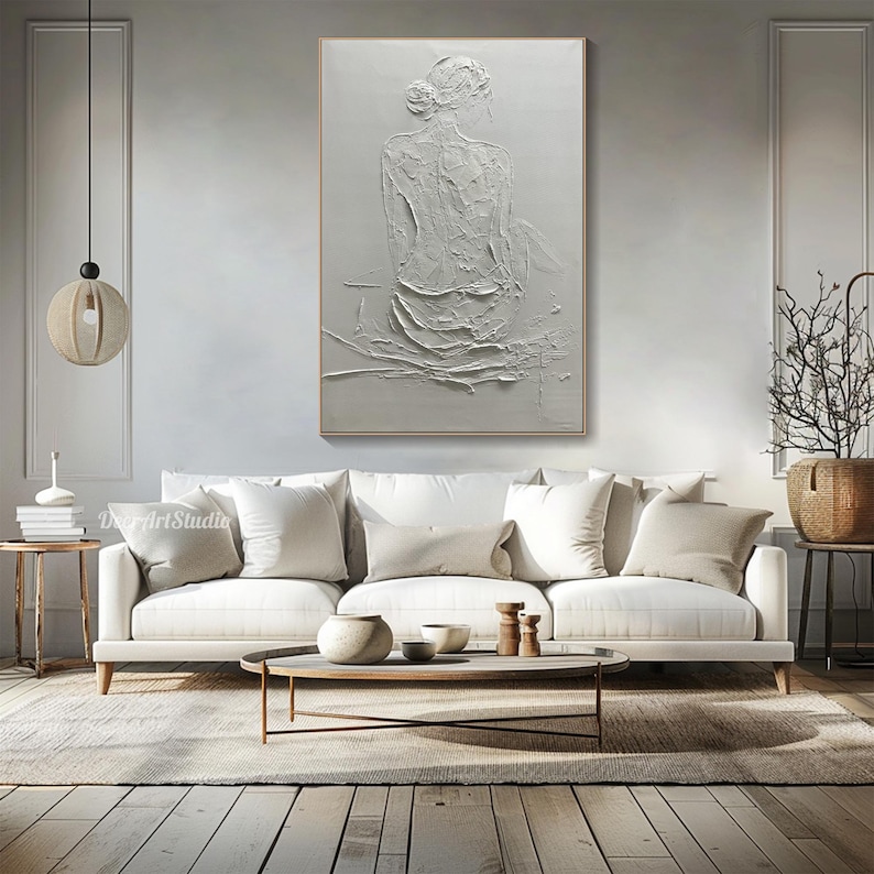 Puede incluir: Pintura blanca texturizada de una persona sentada de espaldas al espectador. La pintura est&aacute; sobre un lienzo blanco y tiene un efecto en relieve tridimensional.