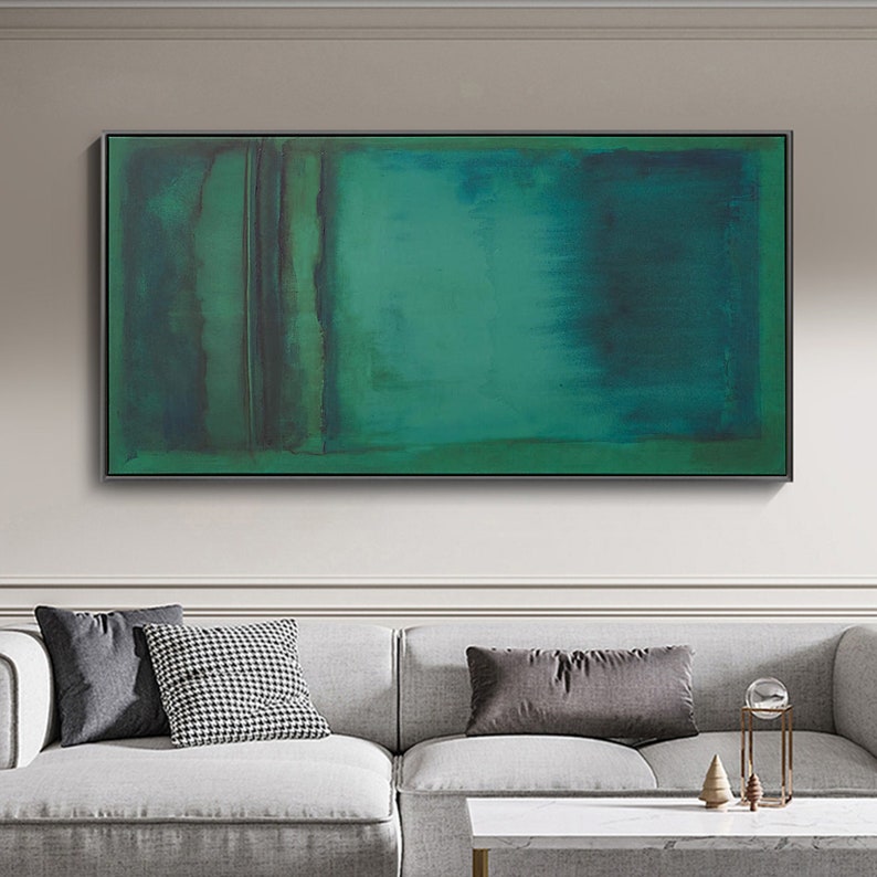Puede incluir: Pintura abstracta con una gama de colores verde y azul. La pintura est&aacute; enmarcada en un marco negro y cuelga de una pared blanca.