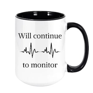 May include: White ceramic mug with a black interior and handle. The mug features the text "Will continue to monitor" in black, along with a black heartbeat line graphic. A simple, yet bold design.