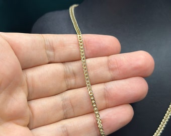 May include: A gold chain necklace with a delicate, intricate design. The chain is made of small, linked pieces that create a fine, delicate look.