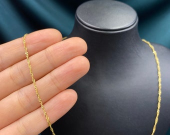 May include: A gold chain necklace with a rope chain design. The chain is on a black display stand.