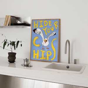 May include: A blue and yellow framed poster with a cartoon seagull with the text "Hide Your Chips" in yellow letters.
