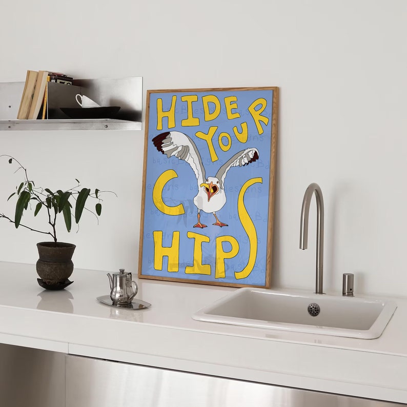 May include: A blue and yellow framed poster with a cartoon seagull with the text "Hide Your Chips" in yellow letters.