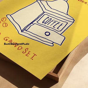 May include: A yellow poster with a blue and white illustration of a coffee grinder. The text "COFFEE" is written on the grinder. The text "GRIND SET" is written in red below the grinder. The text "YOU WOULD UNDERSTAND" is written in red in the upper right corner of the poster.