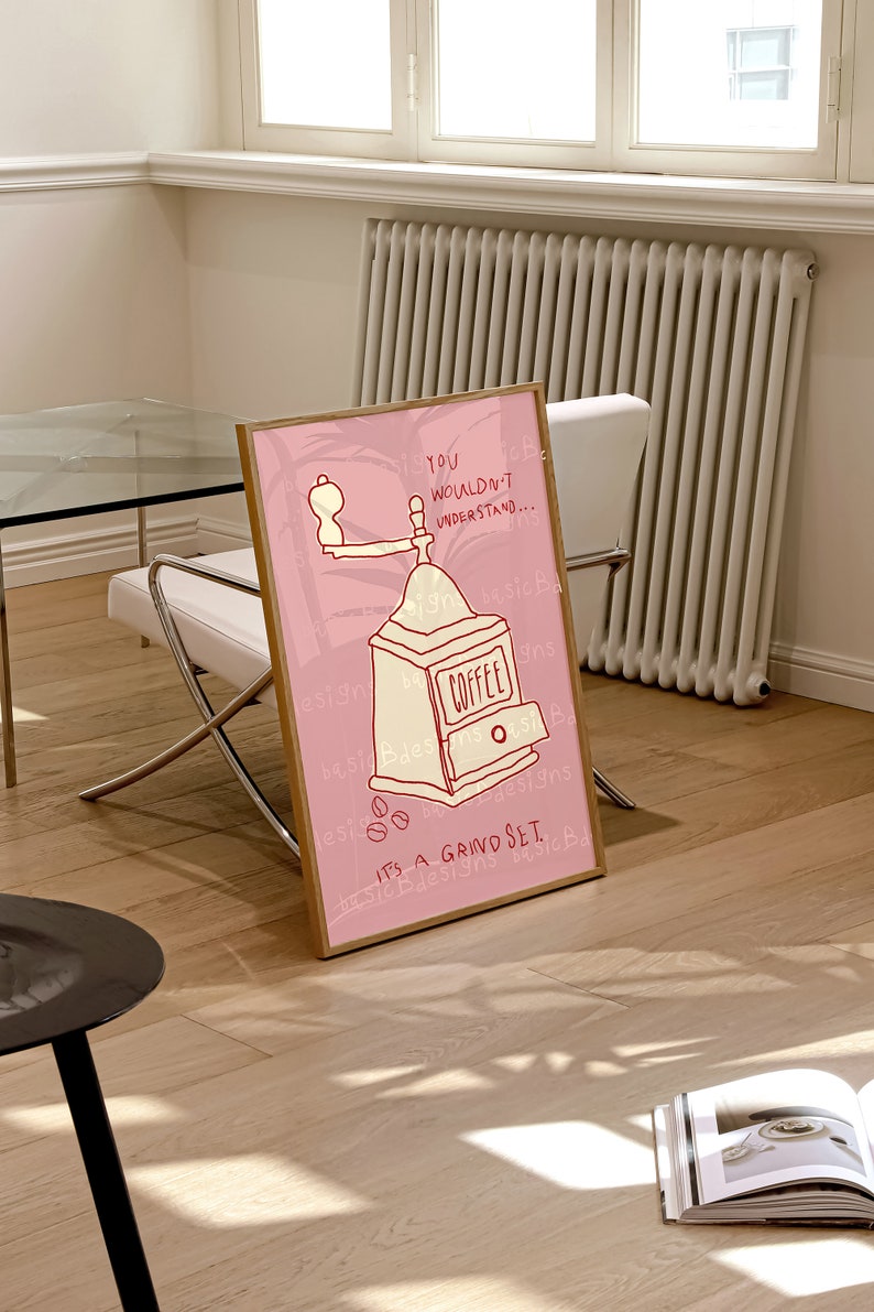 May include: A pink and white framed illustration of a coffee grinder with the text "YOU WOULDN'T UNDERSTAND... IT'S A GRIND SET." and the words "COFFEE" and "basic Bdesigns" repeated throughout the image.