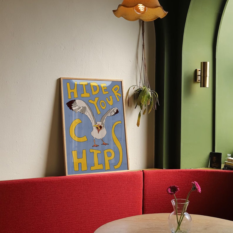 May include: A blue and yellow poster with a cartoon seagull and the text "Hide Your Chips". The poster is hanging on a wall in a restaurant.