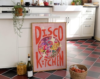 May include: A rectangular framed wall art print with a light pink background featuring a colorful disco ball graphic in the center and the red text "DISCO KITCHEN" above and below the disco ball, accented with white star shapes.