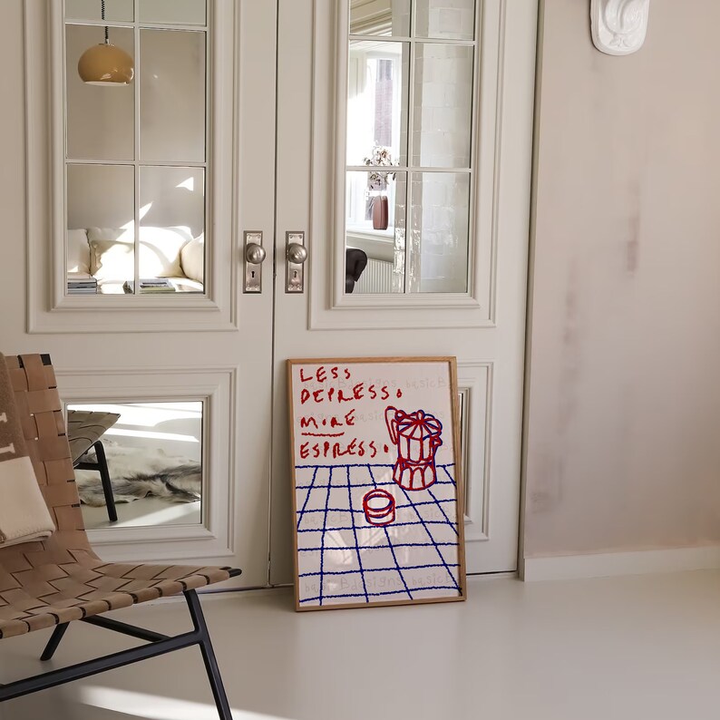 May include: A framed print with a white background and blue grid pattern. The print features red text that reads "Less Depresso More Espresso" and a red and white illustration of a coffee pot.
