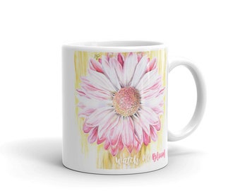 Könnte beinhalten: Weiße Keramiktasse mit einer Illustration einer rosa und weißen Gänseblümchenblume und dem Text "watch me bloom" auf gelbem Hintergrund.