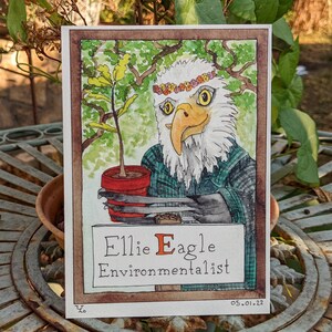 Könnte beinhalten: Aquarell-Illustration eines Adlers mit einer Blumenkrone und einem karierten Hemd, der eine Topfpflanze hält. Der Text lautet "Ellie Eagle Environmentalist".