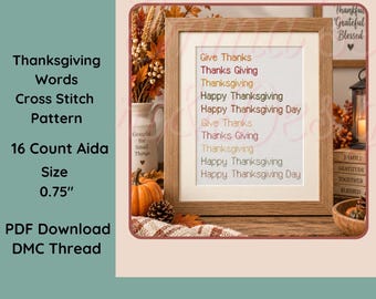 May include: A framed cross stitch pattern featuring the text Give Thanks, Thanks Giving, Thanksgiving, Happy Thanksgiving, and Happy Thanksgiving Day in various colors, displayed in a light wood frame with a white mat on a wooden surface.