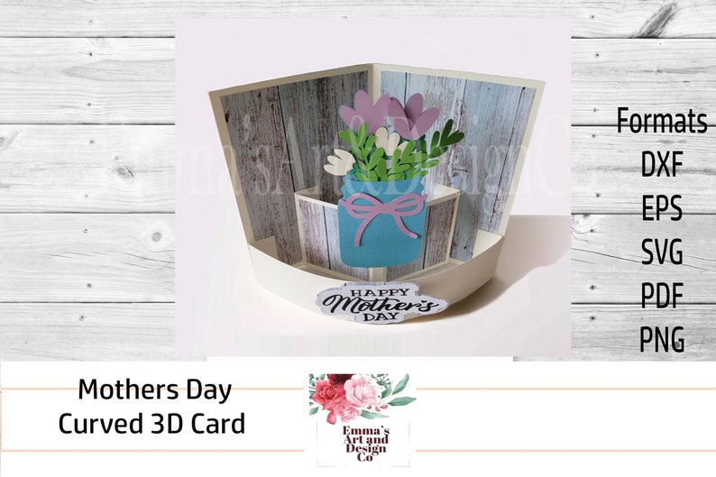 May include: A 3D pop-up card with a woodgrain background. The card features a blue mason jar with a pink bow and a bouquet of pink and white flowers. The card reads "Happy Mother's Day".
