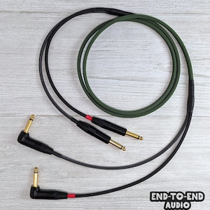 Peut inclure: Deux câbles d'instrument avec des connecteurs à pointe dorée. Un câble est noir, l'autre est vert. Les câbles sont enroulés et ont des accents rouges. Le texte "END-TO-END AUDIO" est dans le coin inférieur droit.