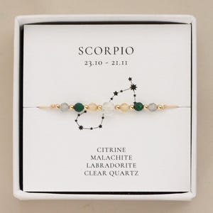 May include: A Scorpio zodiac bracelet featuring citrine, malachite, labradorite, and clear quartz beads on a gold-toned chain. The bracelet is displayed on a white card with the text SCORPIO 23.10 - 21.11, a constellation graphic, and the stone names.