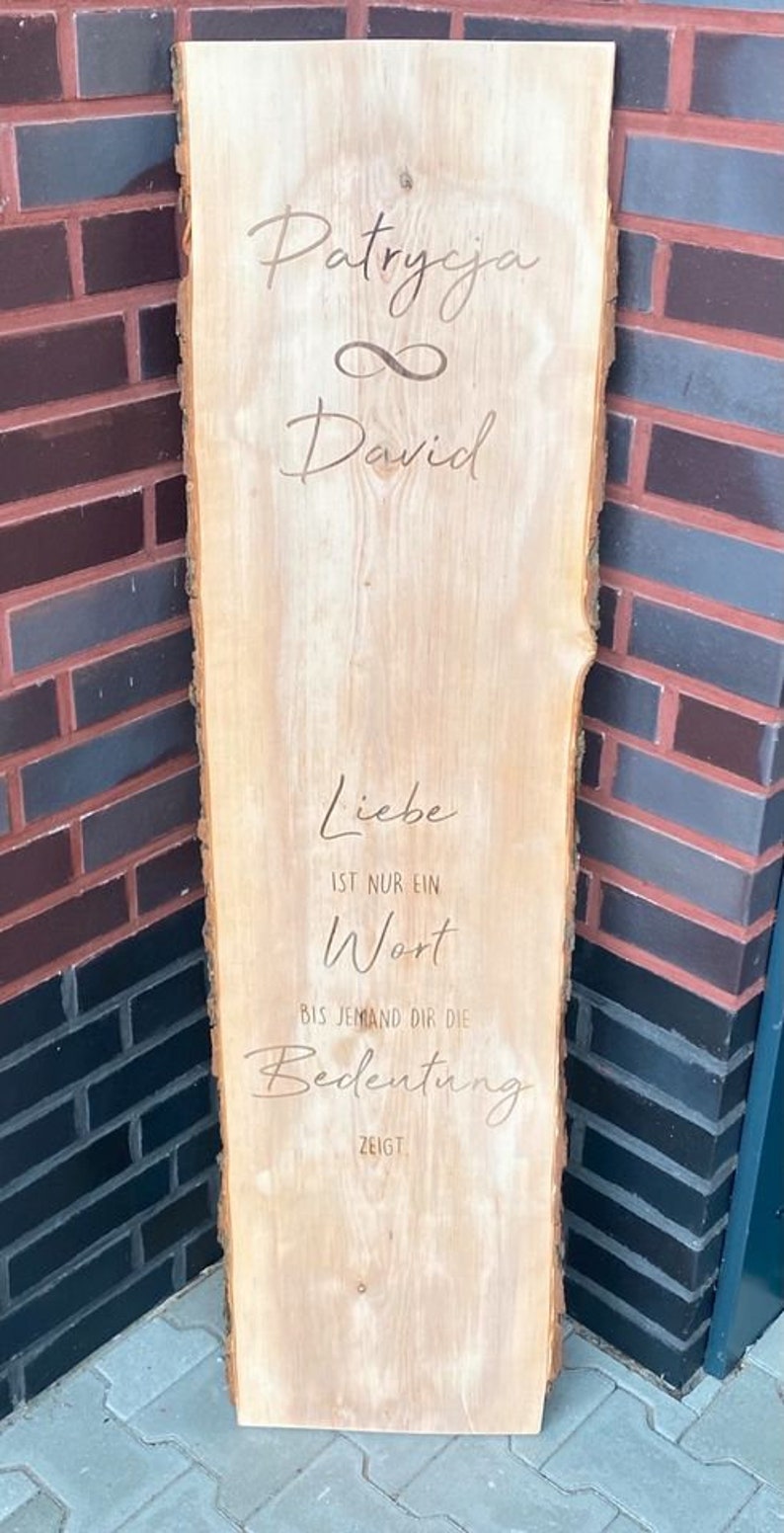 May include: A wooden sign with the names "Patrycja" and "David" written in cursive, with an infinity symbol between them. The sign also has the text "Liebe ist nur ein Wort bis jemand dir die Bedeutung zeigt."