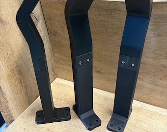 Könnte beinhalten: Drei schwarze Plastik-Tischbeine mit einem geschwungenen Design und einem Loch oben. Die Beine stehen auf einer Holzoberfläche.