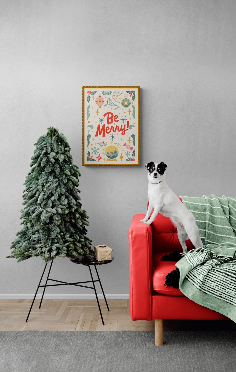 Pu&ograve; includere: Un divano rosso con una coperta a righe verdi e bianche. Un piccolo cane bianco e nero &egrave; in piedi sul divano. Una stampa incorniciata con il testo "Be Merry!" &egrave; appesa al muro dietro il divano. Un piccolo albero di Natale artificiale &egrave; in primo piano.