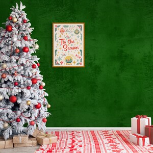 May include: A snowy Christmas tree decorated with red and gold ornaments, red and white garland, and presents underneath. A framed print with the text "Tis the Season" hangs on a green wall behind the tree. A red and white patterned rug is on the floor in front of the tree.