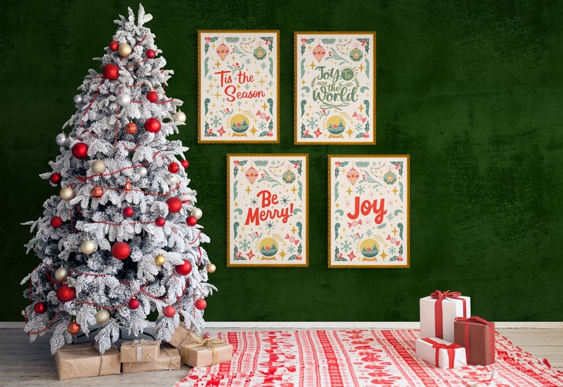 May include: Four framed Christmas prints with festive illustrations and text, including "Tis the Season", "Joy to the World", "Be Merry!" and "Joy", hanging on a green wall with a snowy Christmas tree in the foreground.