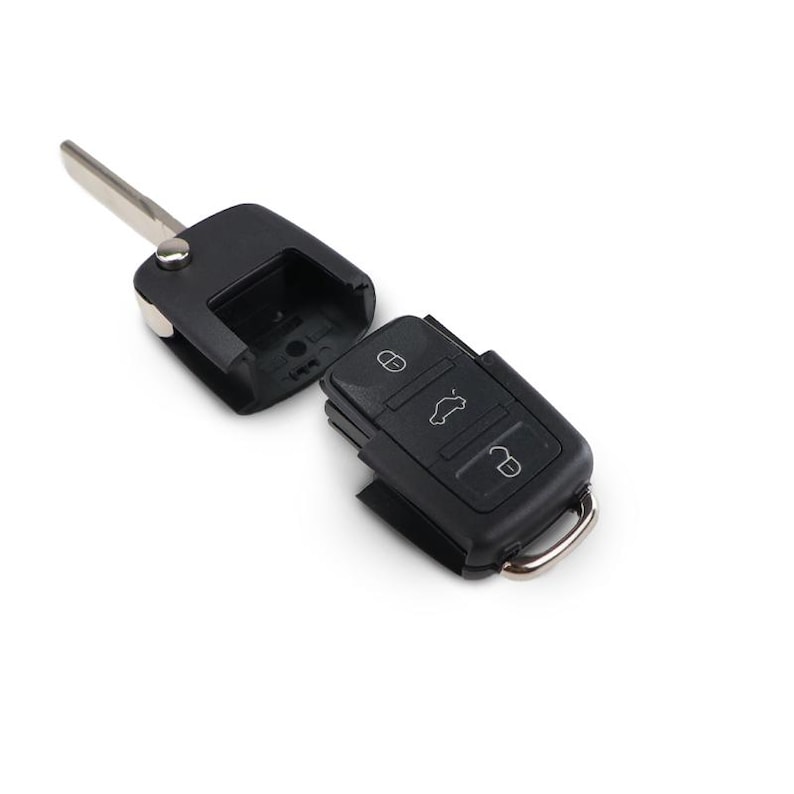 May include: A black car key with a metal key blade and three buttons. The key is in two parts, with the key blade and a section that holds the key's electronics separated from the main body.