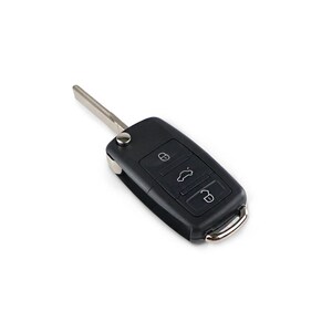 May include: A black car key with a silver key blade. The key has three buttons with icons for locking, unlocking, and opening the trunk. The key is on a white background.