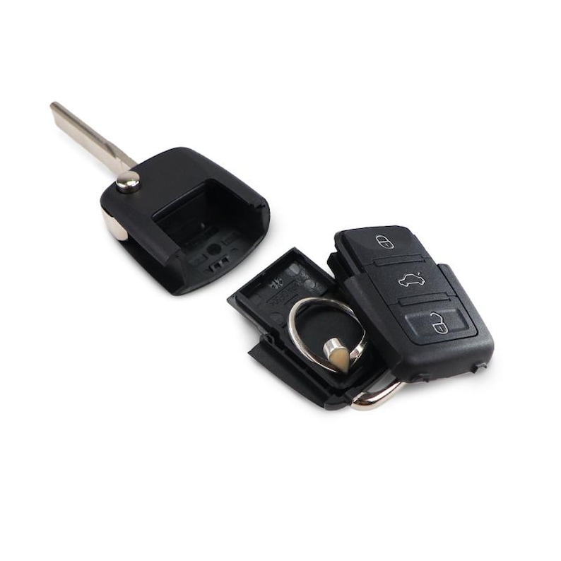 May include: A black car key with a silver key blade and a separate key fob. The key fob has buttons for locking, unlocking, and opening the trunk. The key is disassembled, showing the internal components.