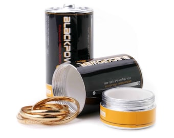 May include: Two black battery-shaped containers with the words "BLACKPOWER" and "Professional Alkaline Battery" printed on them. The containers are open and one contains a stack of gold rings.