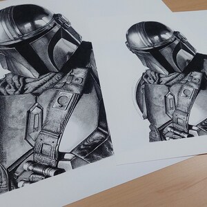 May include: A black and white pencil drawing of a Mandalorian character from the Star Wars franchise. The character is wearing a helmet and armor, and is holding a weapon.