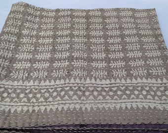 May include: A gray kantha quilt with a white floral pattern and a white geometric border. The quilt is folded in half and has a purple backing.