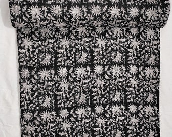 May include: Black and white kantha quilt with a floral pattern. The quilt is rolled up and the fabric is soft and textured.