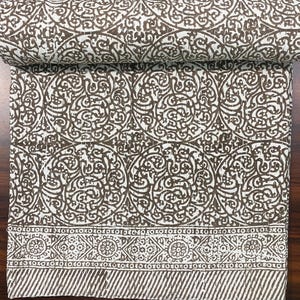 May include: A white cotton kantha quilt with a brown floral pattern. The quilt has a border with a repeating geometric design.