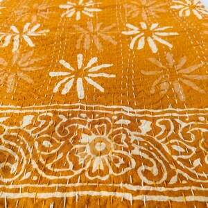 May include: A mustard yellow kantha quilt with a white floral pattern. The quilt has a border with a white paisley design.