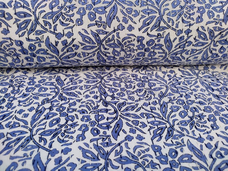 May include: White fabric with a blue floral pattern. The fabric is folded in half, showing the pattern on both sides.
