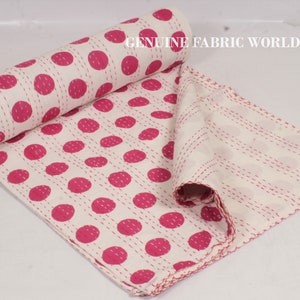 May include: White cotton kantha quilt with pink polka dots. The quilt is folded and rolled up, showing the stitching detail. The text "GENUINE FABRIC WORLD" is visible in the top right corner of the image.